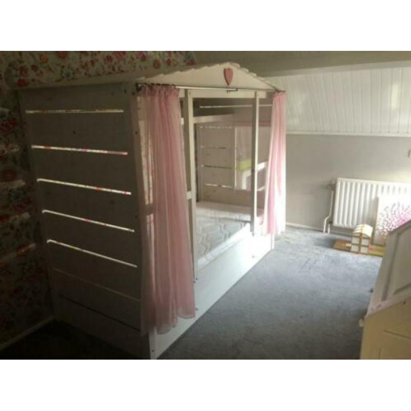 Gezellig wit bedhuis met roze gordijntjes en roze nachtlamp