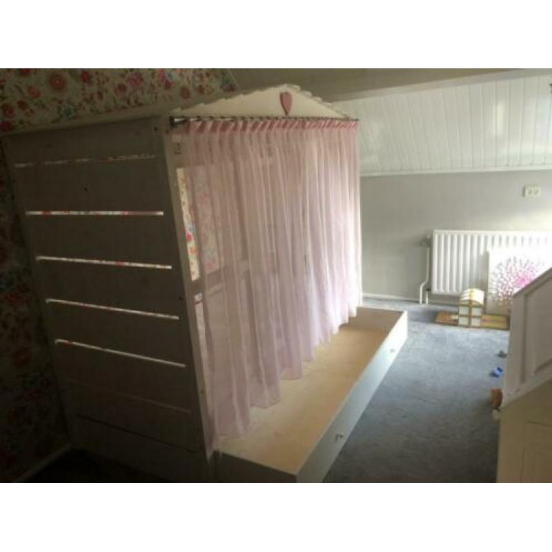 Gezellig wit bedhuis met roze gordijntjes en roze nachtlamp